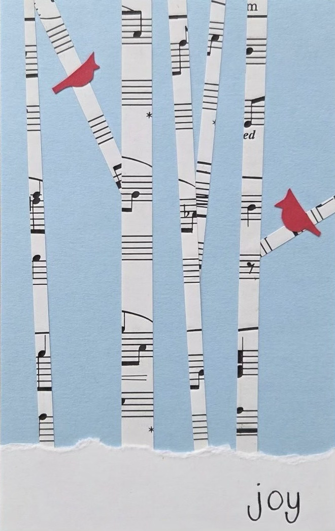 Collage of birch trees made from sheet music on a blue background with two red cardinals. Snow is at the bottom, and "joy" is written in black.