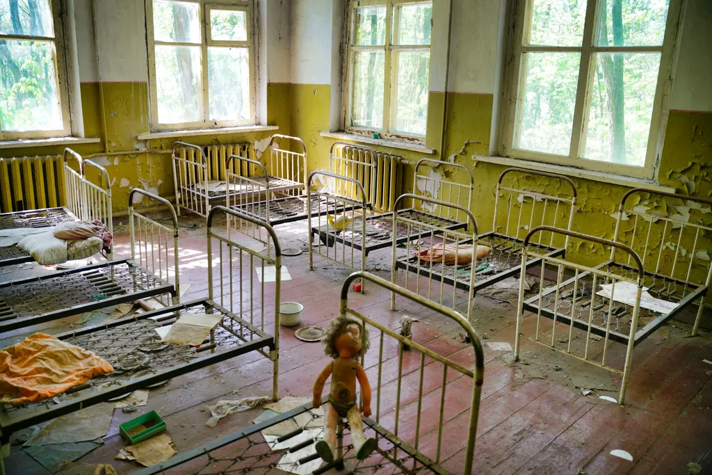 Abandoned orphange in Chernobyl, Ukraine. Metal frame beds. children's toys strewn about. Peeling paint.